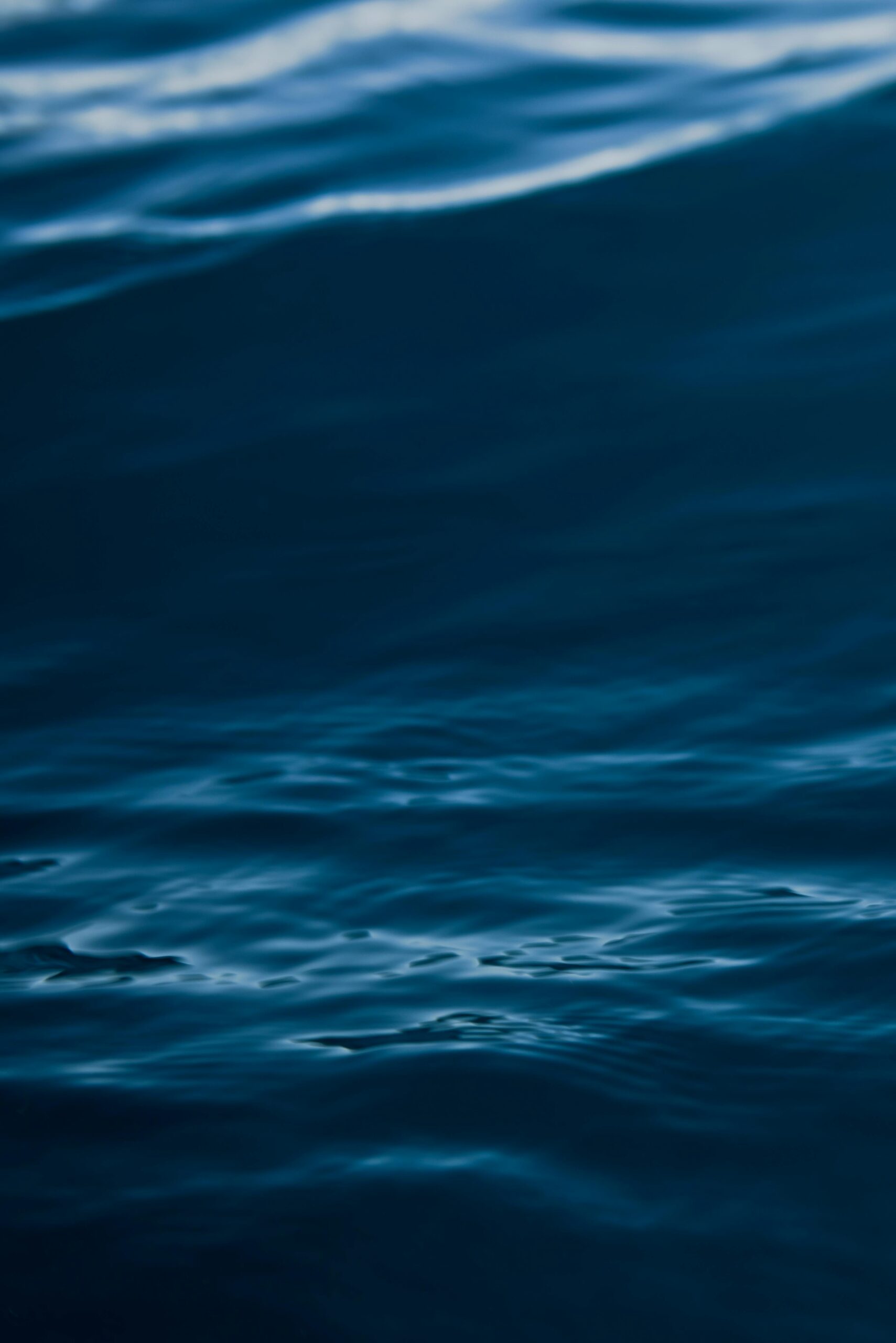 A tranquil view of dark blue ocean waves with gentle ripples and motion.